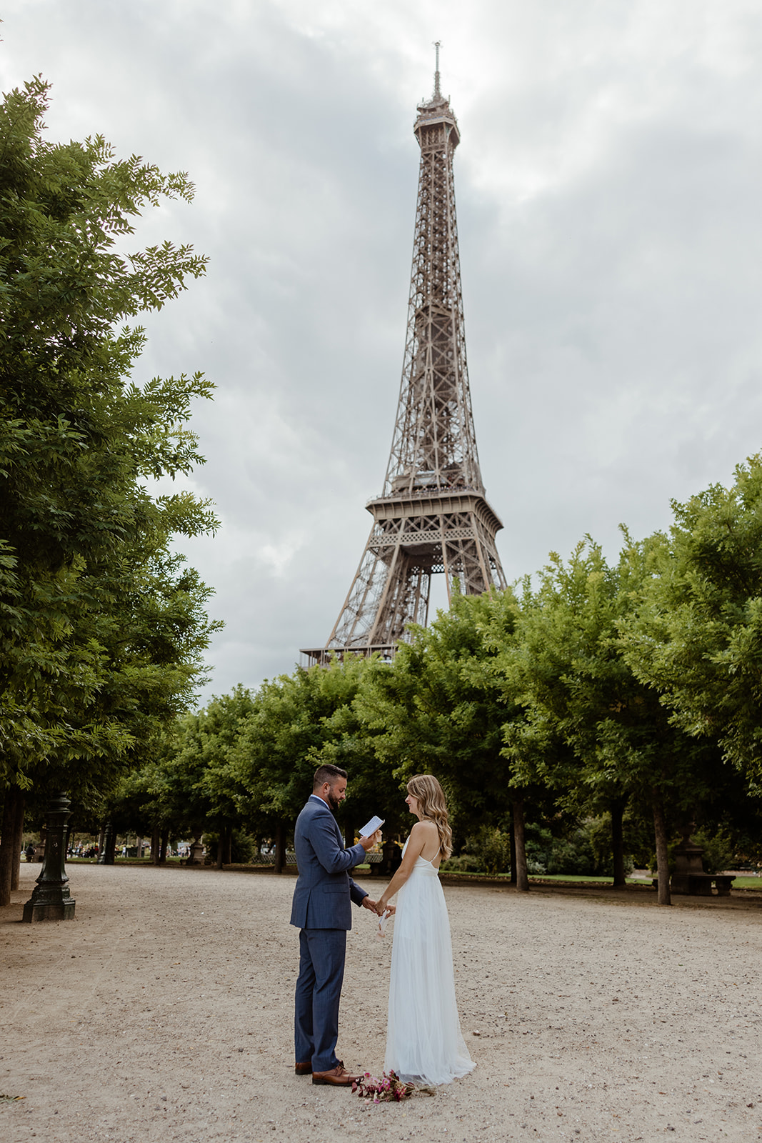 Wide view of Ashley and Danny eloping under the Eiffel Tower in Paris, photographed by Boston elopement photographer and officiant Erin of Boston